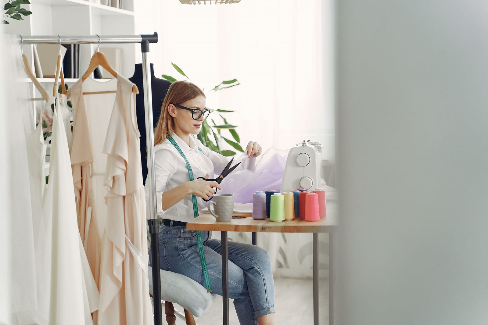 Frau näht konzentriert an einem Kleidungsstück im Atelier